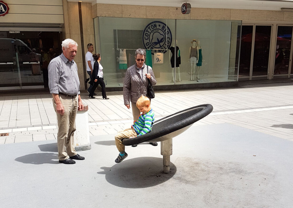 Grandparents watching child spin and play in the Kalotta Turner