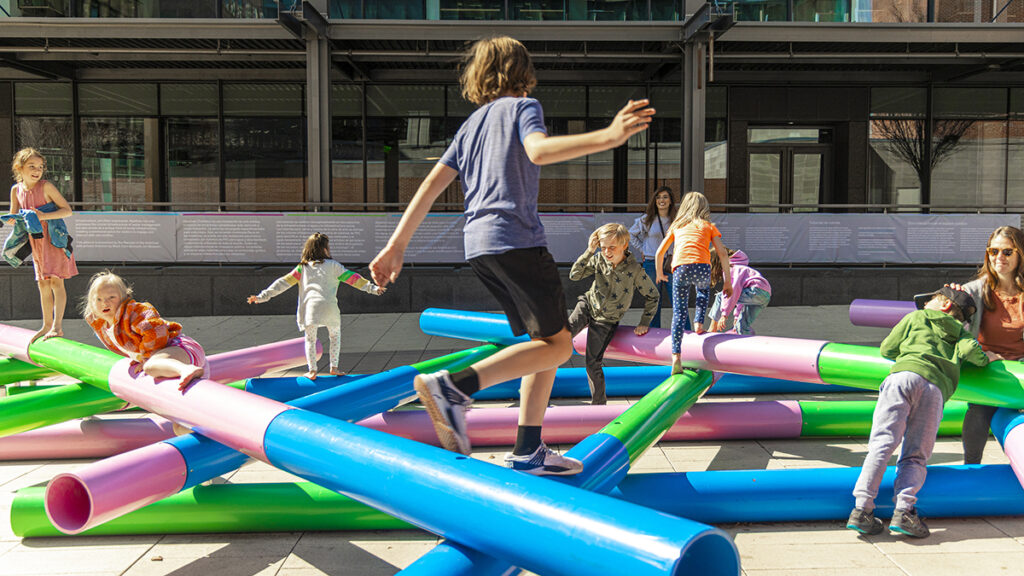 Children jumping on the art installation pipeplines by Jamrozik and Kempster