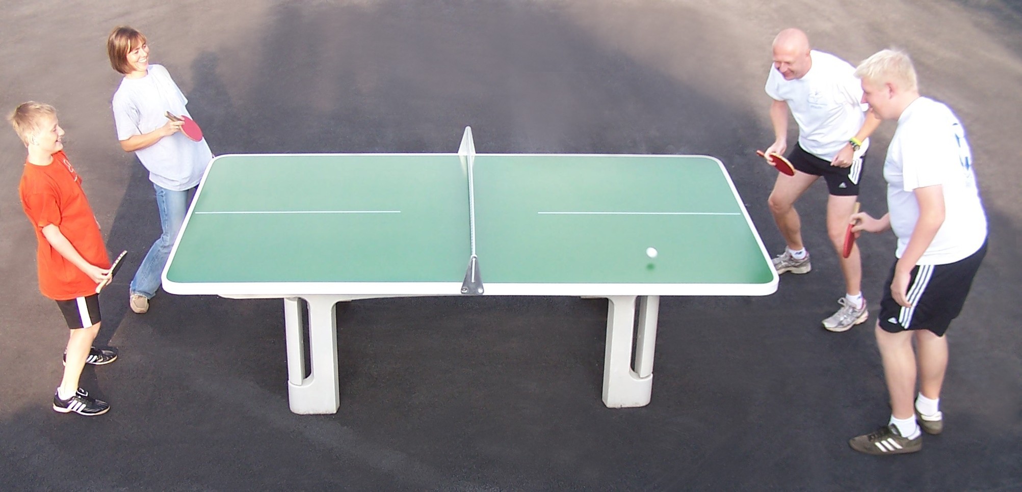 Older adults and children playing table tennis.